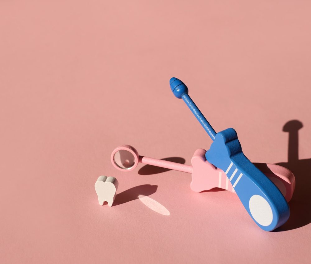 Model Tooth and Dental Probe and Dental mirror on pink background.