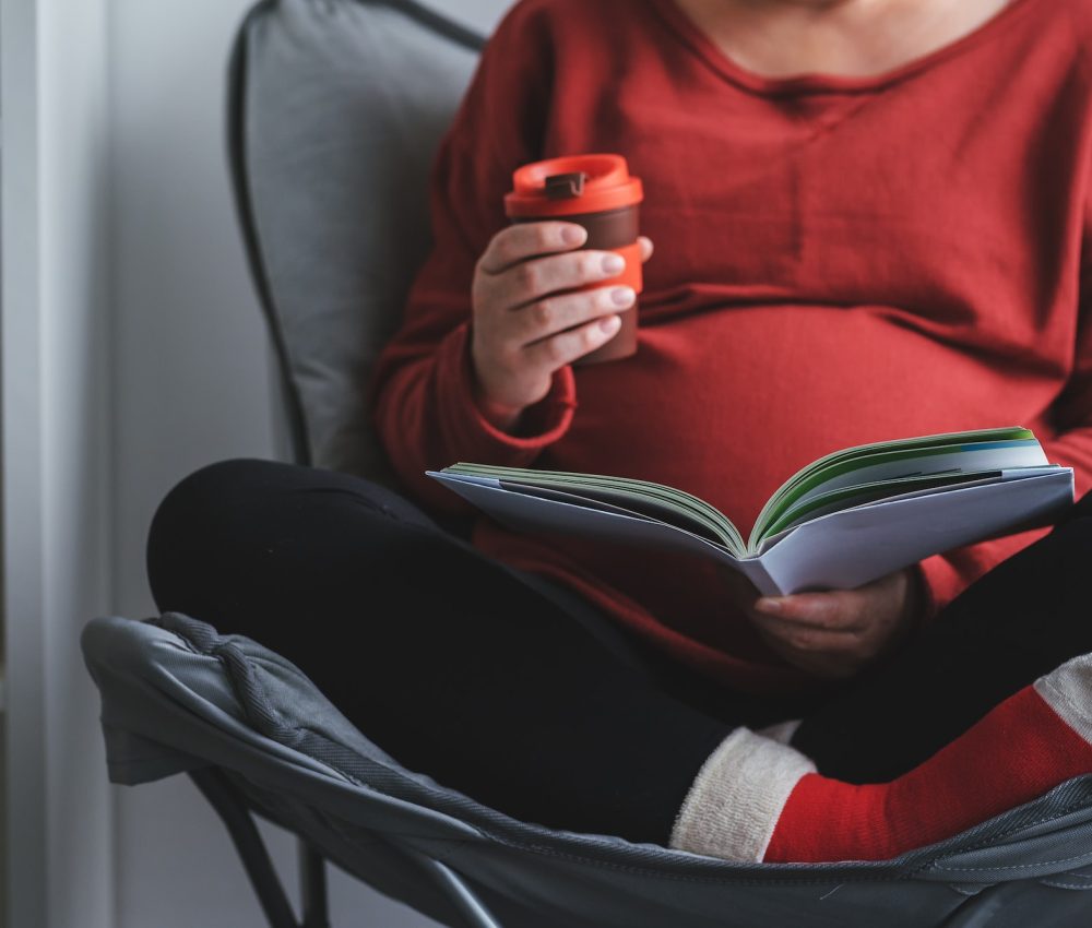 Pregnant woman reading book in living room